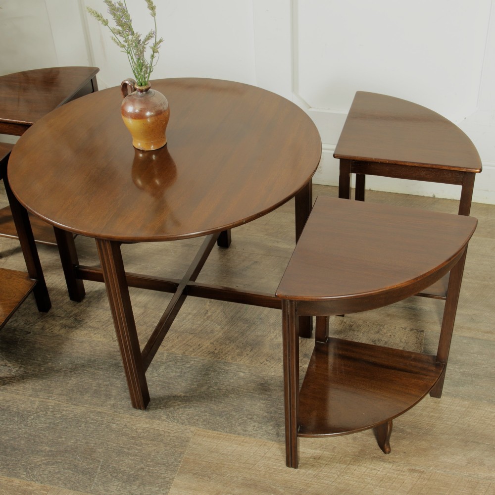 An Edwardian mahogany nest of five circular tables featuring four individual quarter-circle side tables stacked beneath the central round table. View II