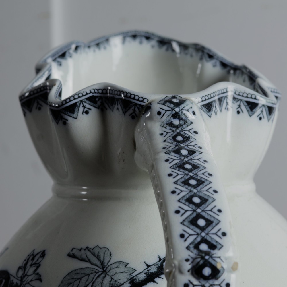 An early 20th-century white ceramic wash set featuring a large ewer and two chamber pots decorated with a black botanical blackberry transferware pattern. View VIII