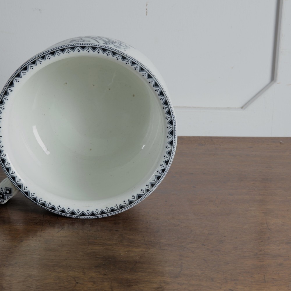 An early 20th-century white ceramic wash set featuring a large ewer and two chamber pots decorated with a black botanical blackberry transferware pattern. View X