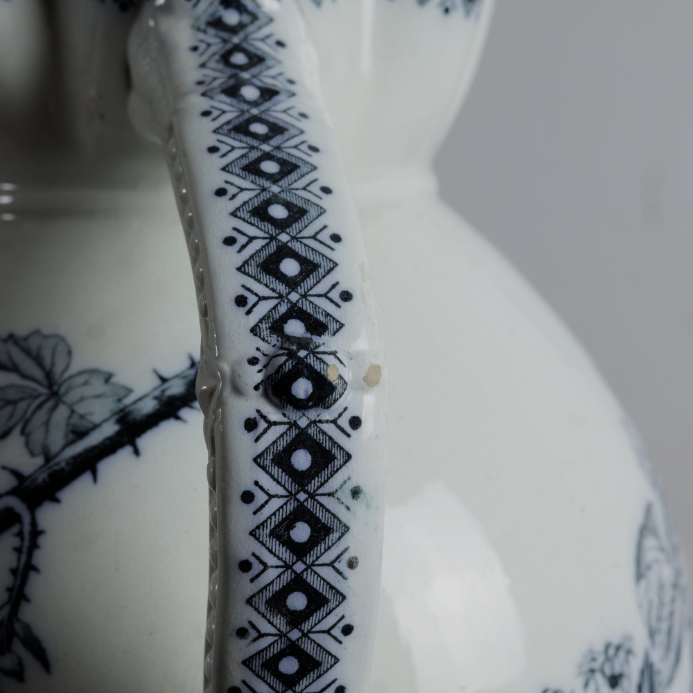 An early 20th-century white ceramic wash set featuring a large ewer and two chamber pots decorated with a black botanical blackberry transferware pattern. View XV