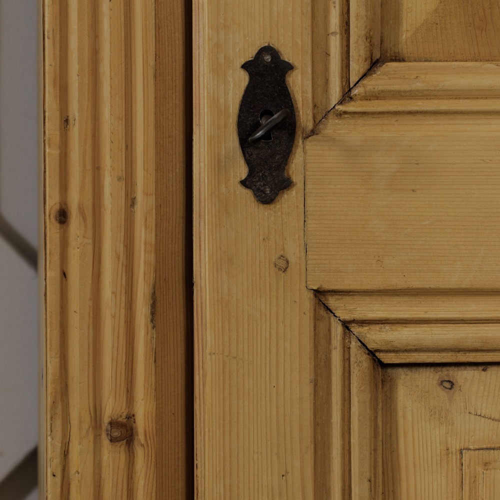 A tall single door stripped pine armoire featuring fielded panels, fluted side pilasters, and turned bun feet. View XI