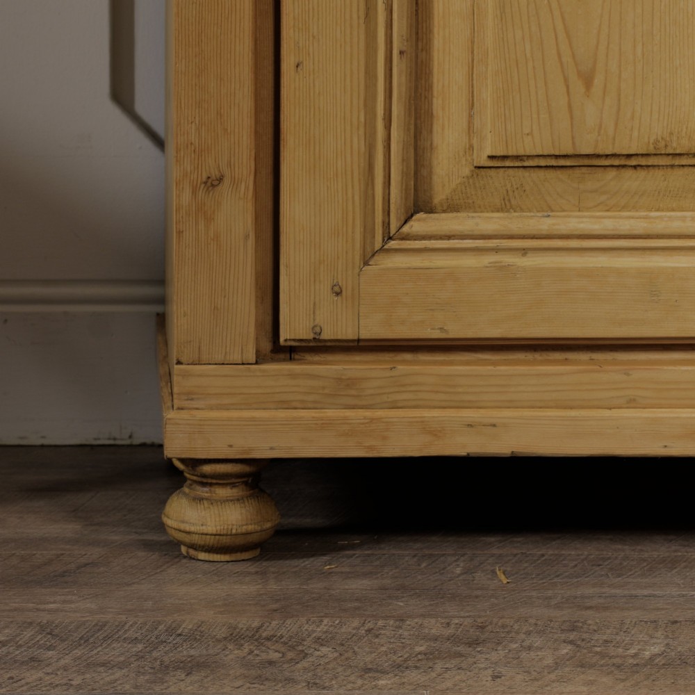 A tall single door stripped pine armoire featuring fielded panels, fluted side pilasters, and turned bun feet. View XII