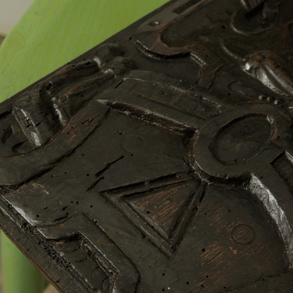 A rectangular dark oak timber panel featuring a high-relief hand carving of a winged cherub head surrounded by intricate scrollwork and geometric strapwork. View VI