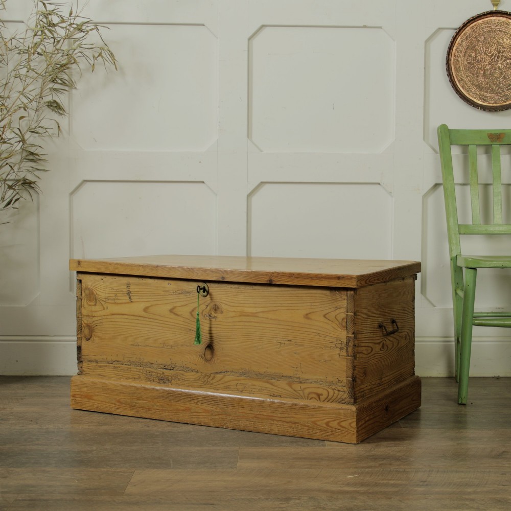 A rectangular Victorian pitch pine storage trunk featuring visible dovetail joinery, an iron keyhole escutcheon, metal side handles, and a plinth base. View III