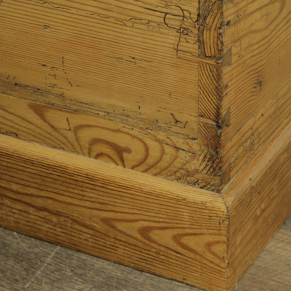 A rectangular Victorian pitch pine storage trunk featuring visible dovetail joinery, an iron keyhole escutcheon, metal side handles, and a plinth base. View IX