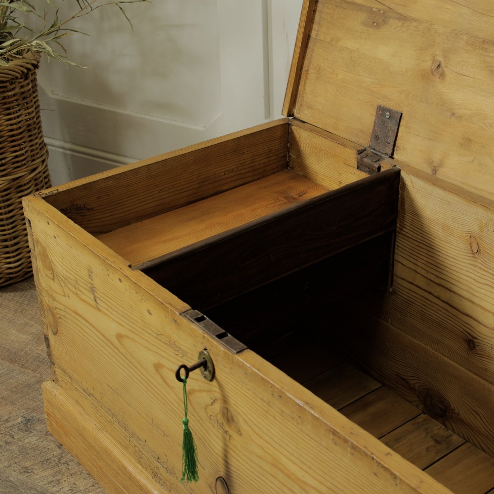 A rectangular Victorian pitch pine storage trunk featuring visible dovetail joinery, an iron keyhole escutcheon, metal side handles, and a plinth base. View X