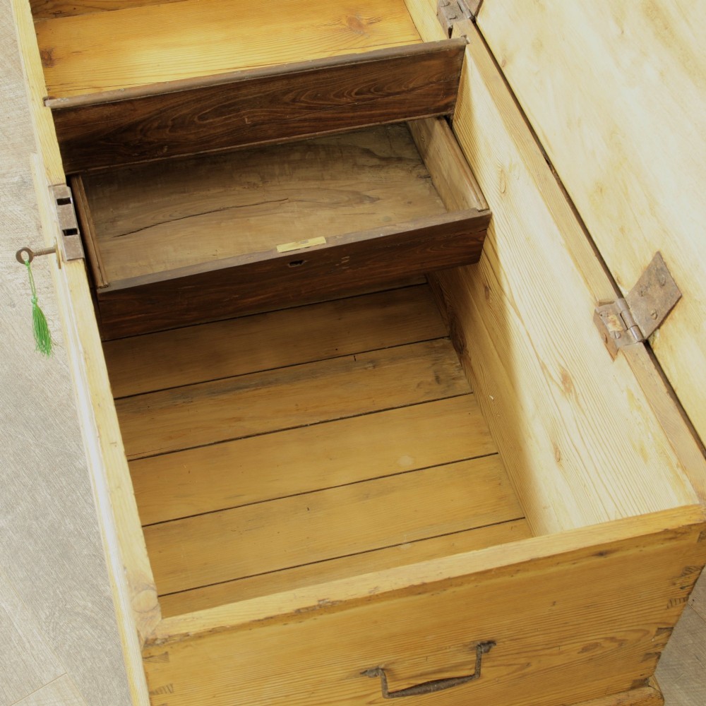 A rectangular Victorian pitch pine storage trunk featuring visible dovetail joinery, an iron keyhole escutcheon, metal side handles, and a plinth base. View XII