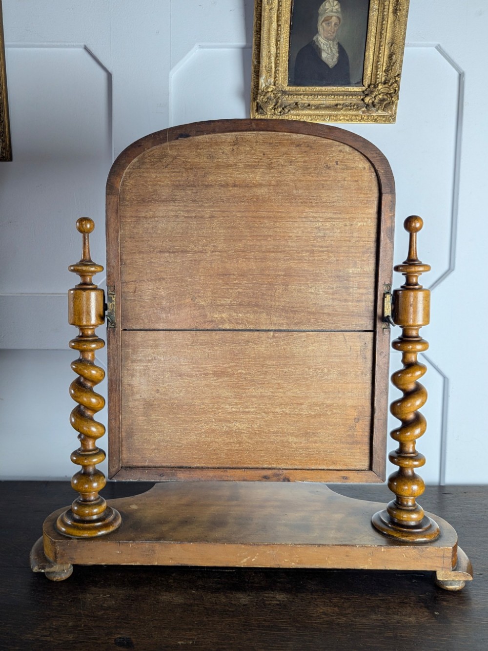 A Victorian satinwood toilet mirror featuring twin barley twist uprights, a curved base, and an arched tilting frame with mercury glass. View V