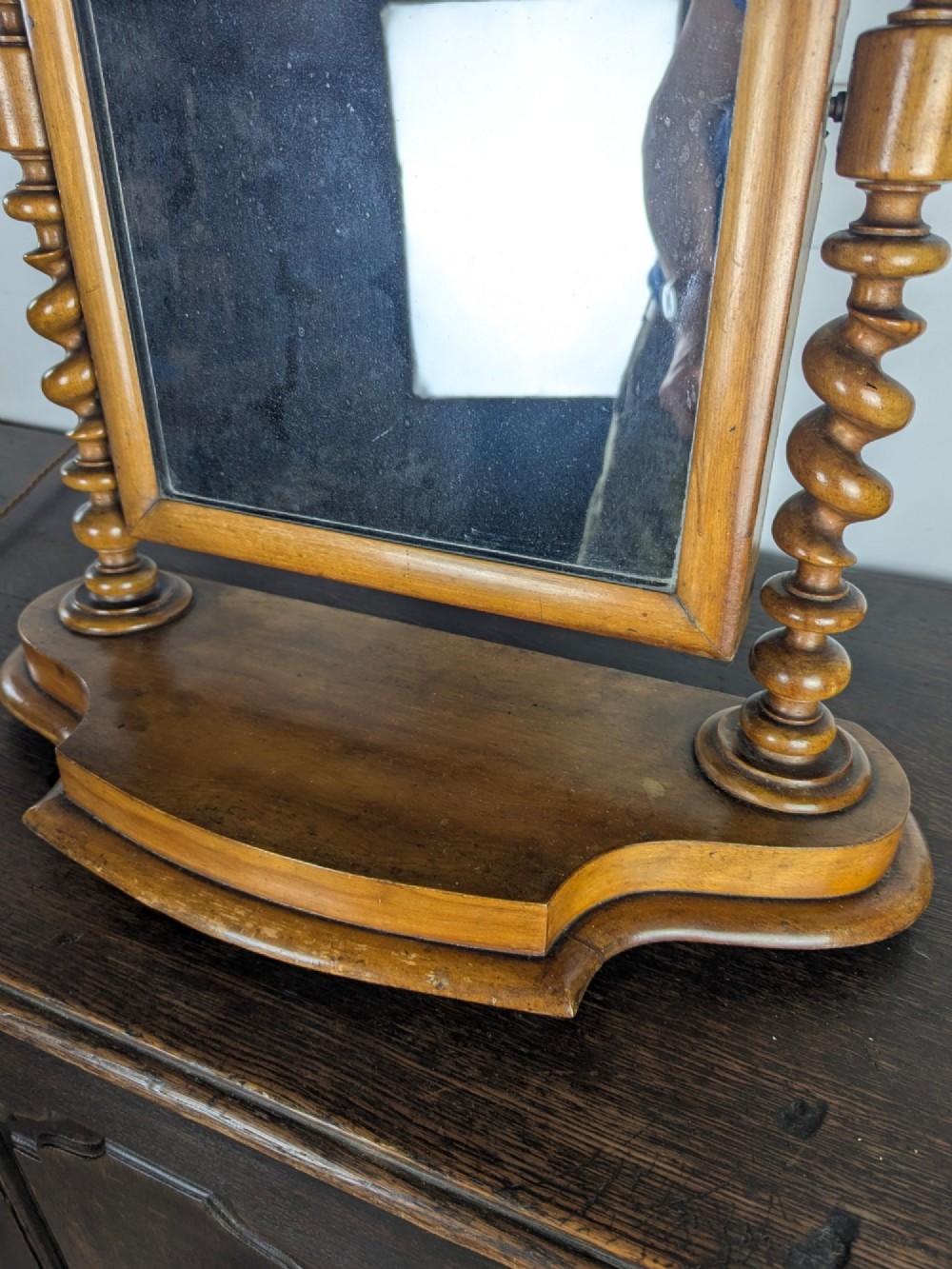 A Victorian satinwood toilet mirror featuring twin barley twist uprights, a curved base, and an arched tilting frame with mercury glass. View VI