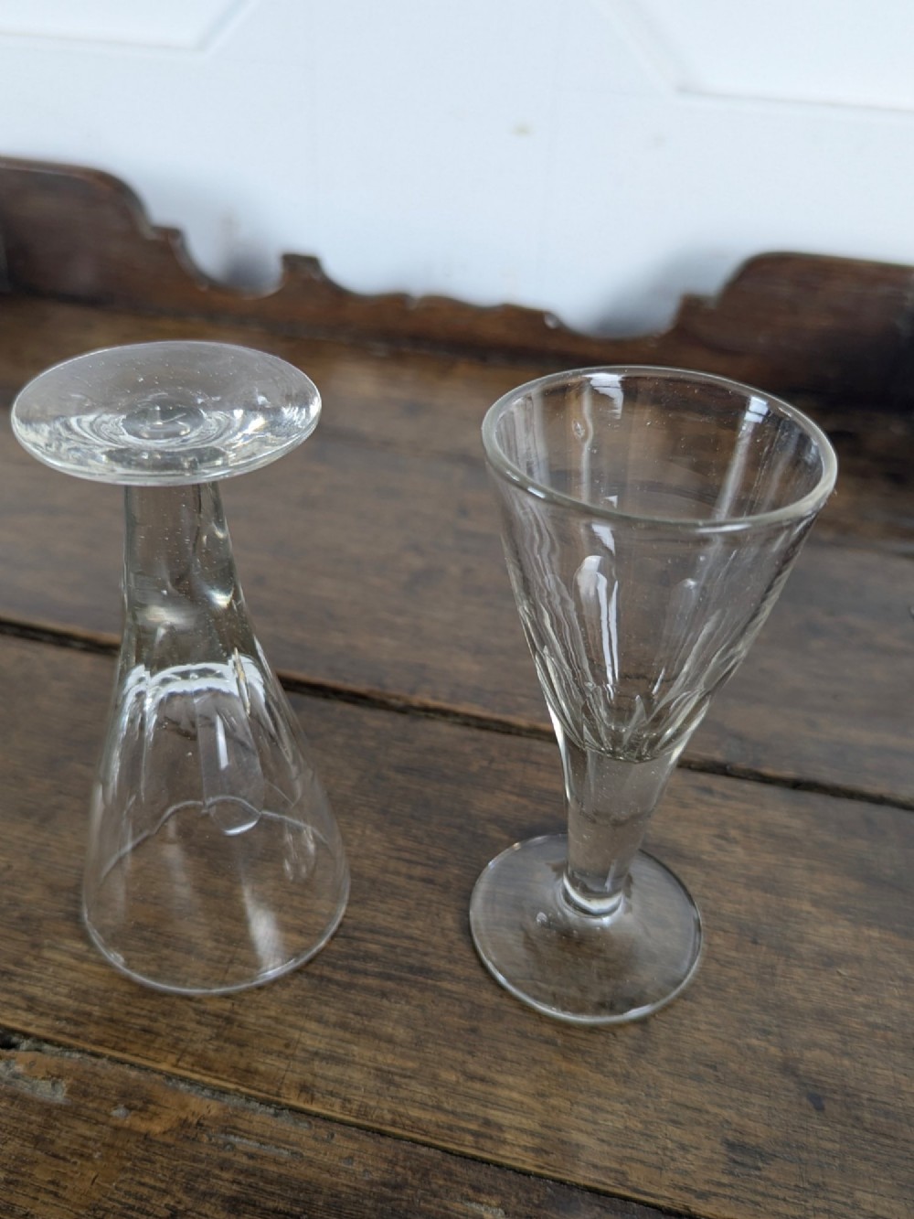 A set of seven clear Victorian glass sherry flutes featuring thumb-cut facet details on conical bowls and short turned stems. View V