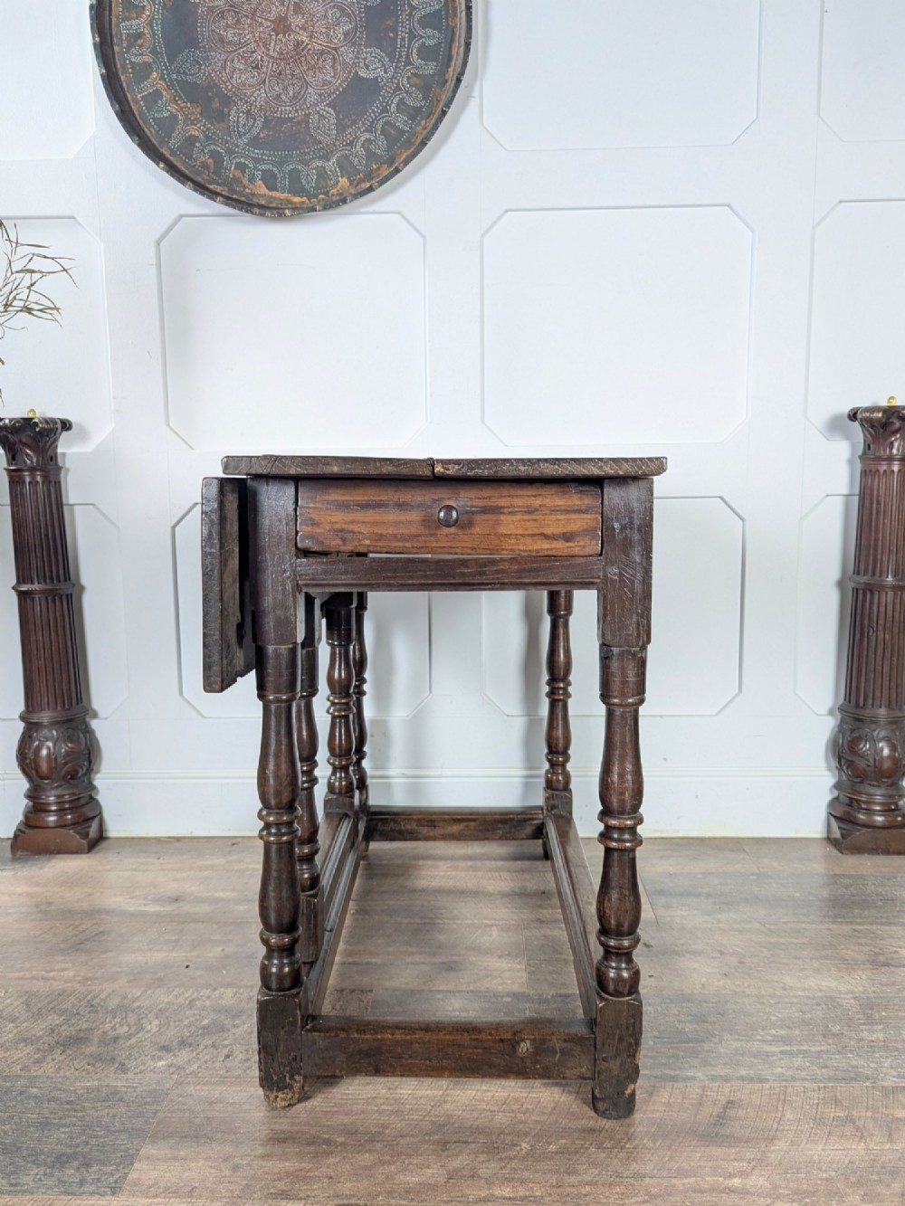 An eighteenth-century dark oak gateleg table with drop leaves, turned legs, stretchers, and a single end drawer. View VII