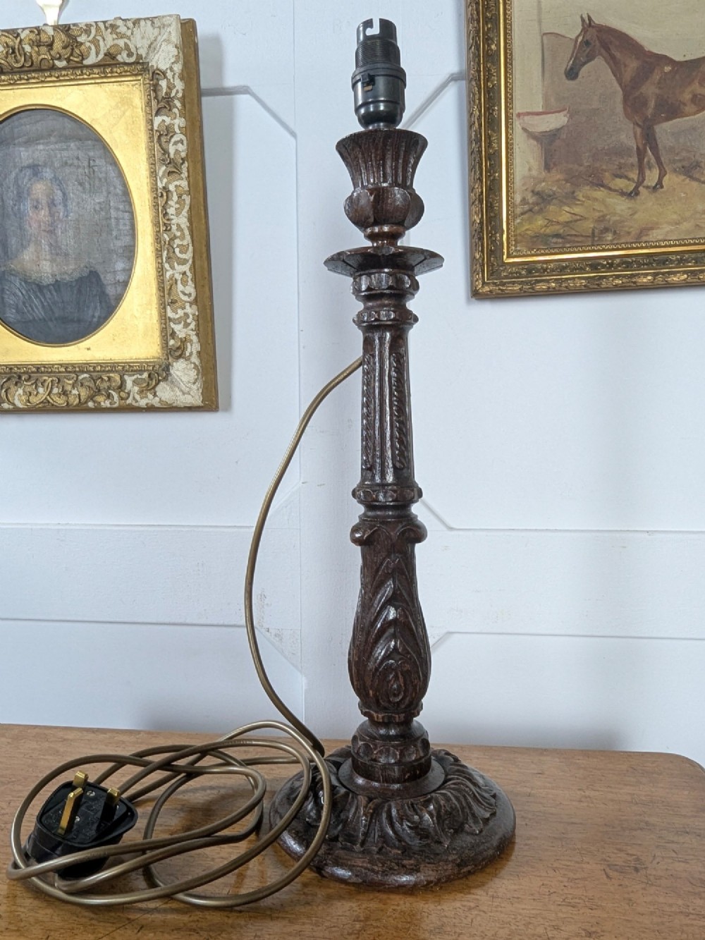 A late Victorian carved dark oak candlestick table lamp base featuring detailed acanthus leaf carvings and an exposed filament bulb. View II