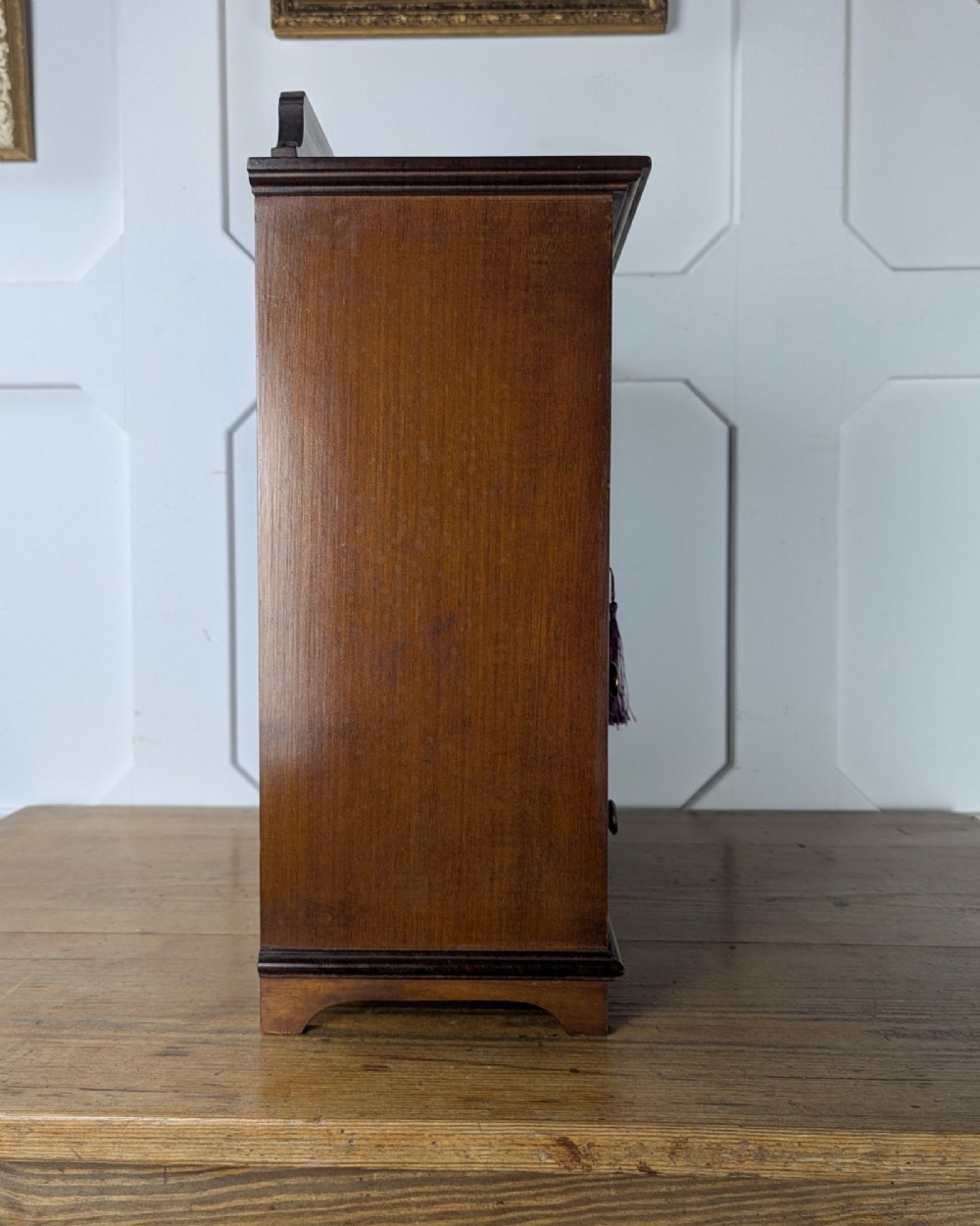 A late nineteenth-century warm brown wooden smokers cabinet featuring an open shelf over two drawers on the left, a single inlaid door on the right, and brass hardware. View V
