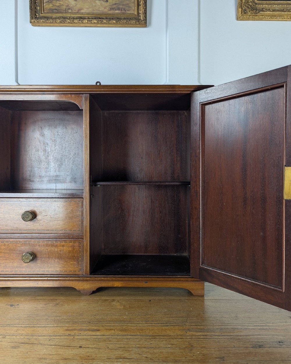 A late nineteenth-century warm brown wooden smokers cabinet featuring an open shelf over two drawers on the left, a single inlaid door on the right, and brass hardware. View VIII