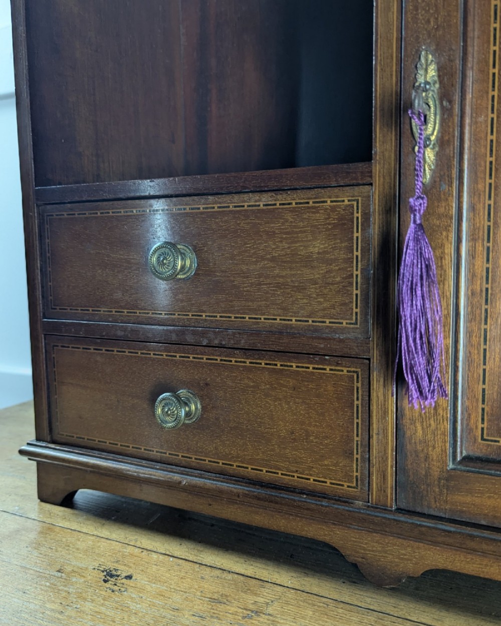 A late nineteenth-century warm brown wooden smokers cabinet featuring an open shelf over two drawers on the left, a single inlaid door on the right, and brass hardware. View IX