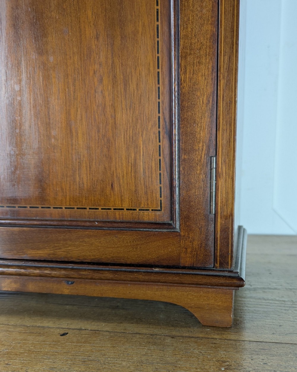 A late nineteenth-century warm brown wooden smokers cabinet featuring an open shelf over two drawers on the left, a single inlaid door on the right, and brass hardware. View X