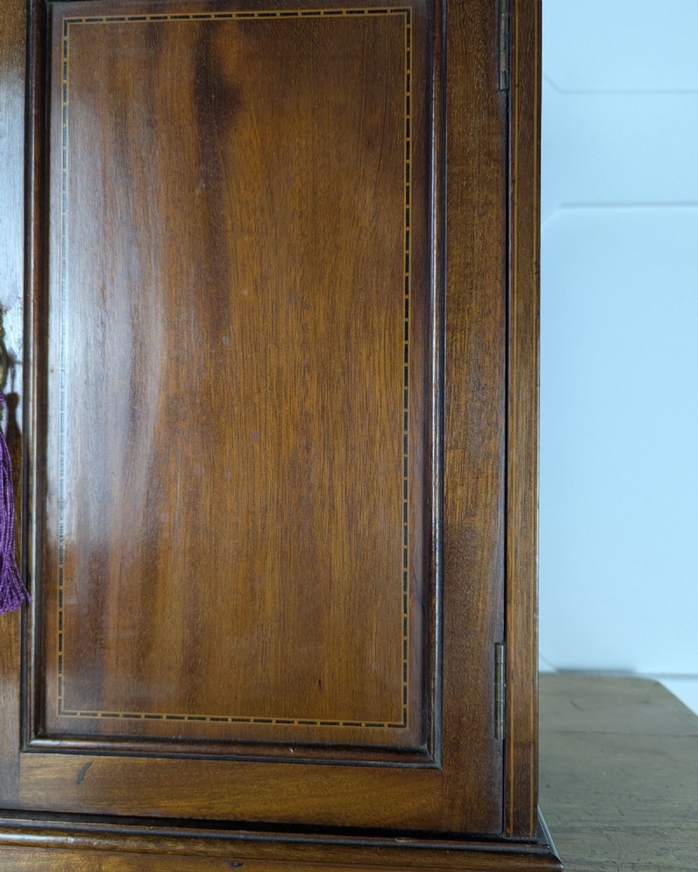 A late nineteenth-century warm brown wooden smokers cabinet featuring an open shelf over two drawers on the left, a single inlaid door on the right, and brass hardware. View XI