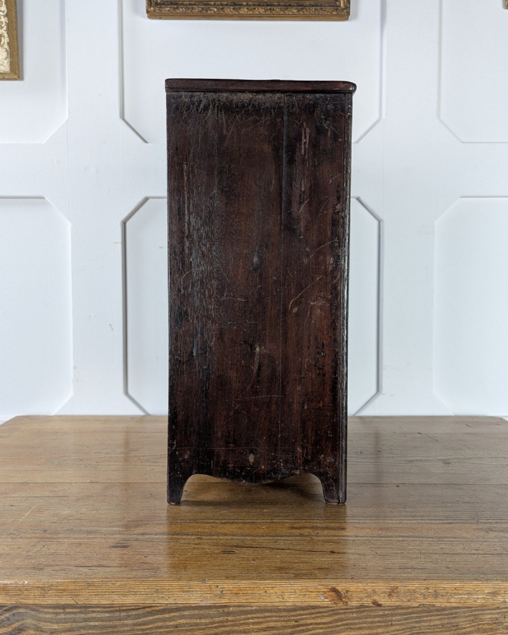 A 19th-century miniature wooden chest of drawers with a dark stained finish, two small top drawers over three long drawers, turned knobs, and brass escutcheons. View V