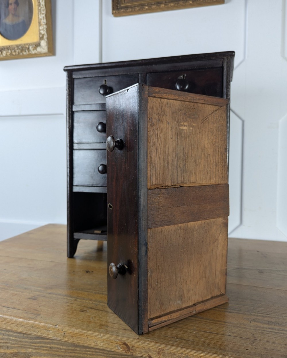 A 19th-century miniature wooden chest of drawers with a dark stained finish, two small top drawers over three long drawers, turned knobs, and brass escutcheons. View XI
