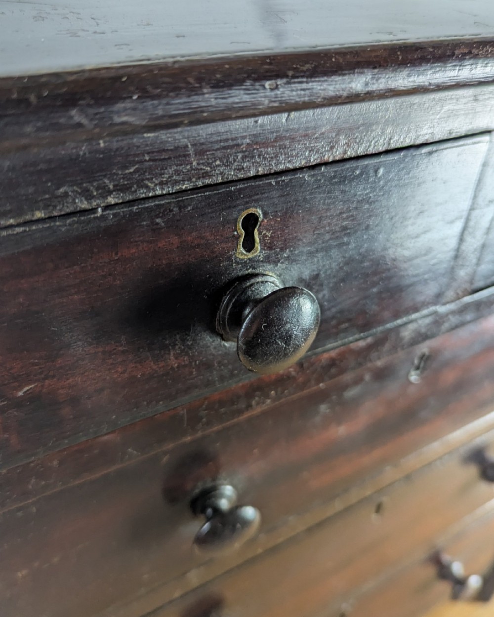 A 19th-century miniature wooden chest of drawers with a dark stained finish, two small top drawers over three long drawers, turned knobs, and brass escutcheons. View XIV