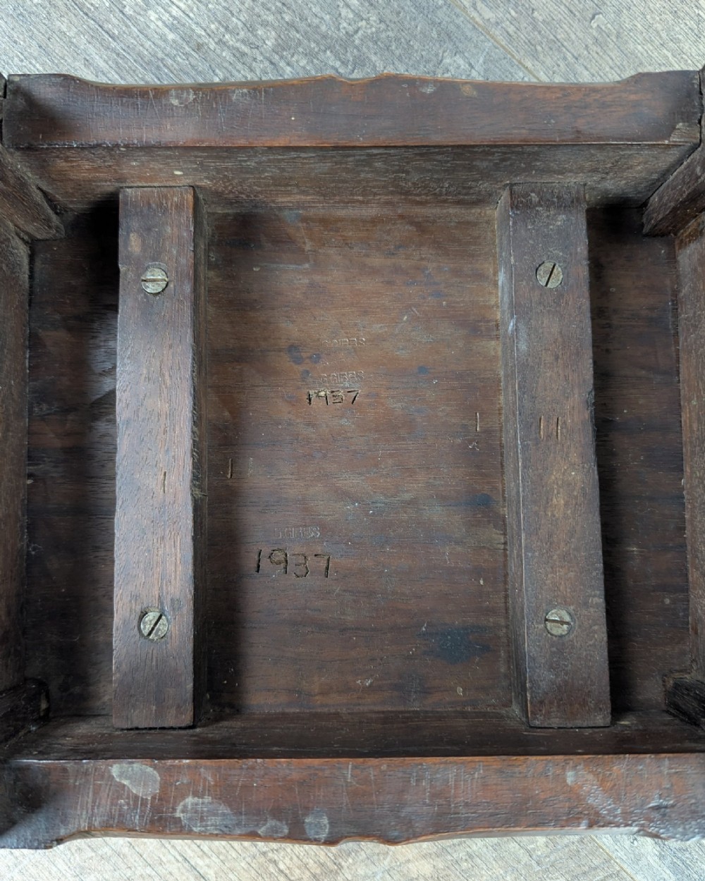 A rectangular dark oak low stool featuring hand-carved notch decorations along the apron and straight legs. View X