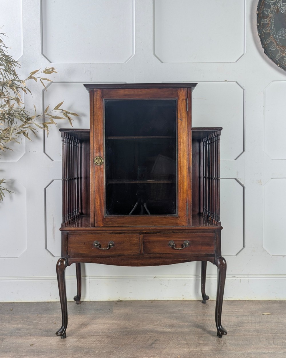 An early 20th-century mahogany music cabinet featuring a central glazed door flanked by turned spindle galleries, set above two drawers on cabriole legs. View II