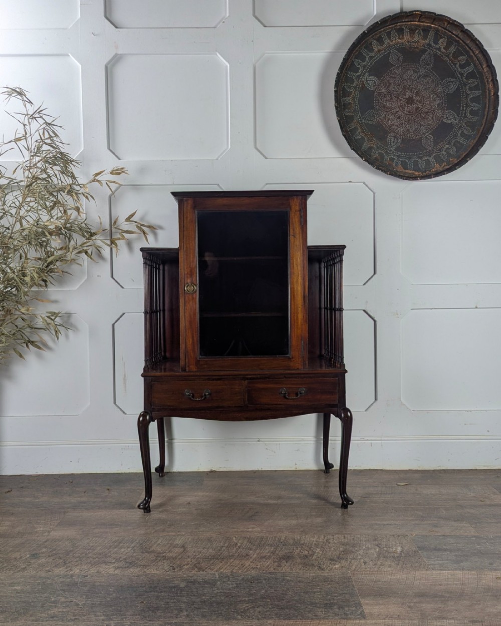 An early 20th-century mahogany music cabinet featuring a central glazed door flanked by turned spindle galleries, set above two drawers on cabriole legs. View VI