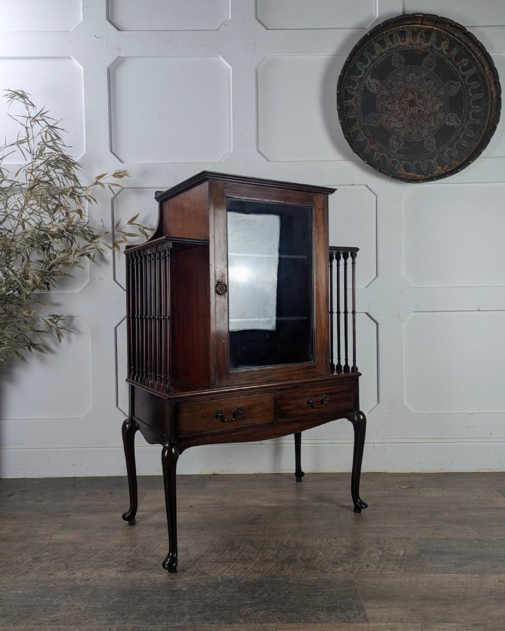 An early 20th-century mahogany music cabinet featuring a central glazed door flanked by turned spindle galleries, set above two drawers on cabriole legs. View VII