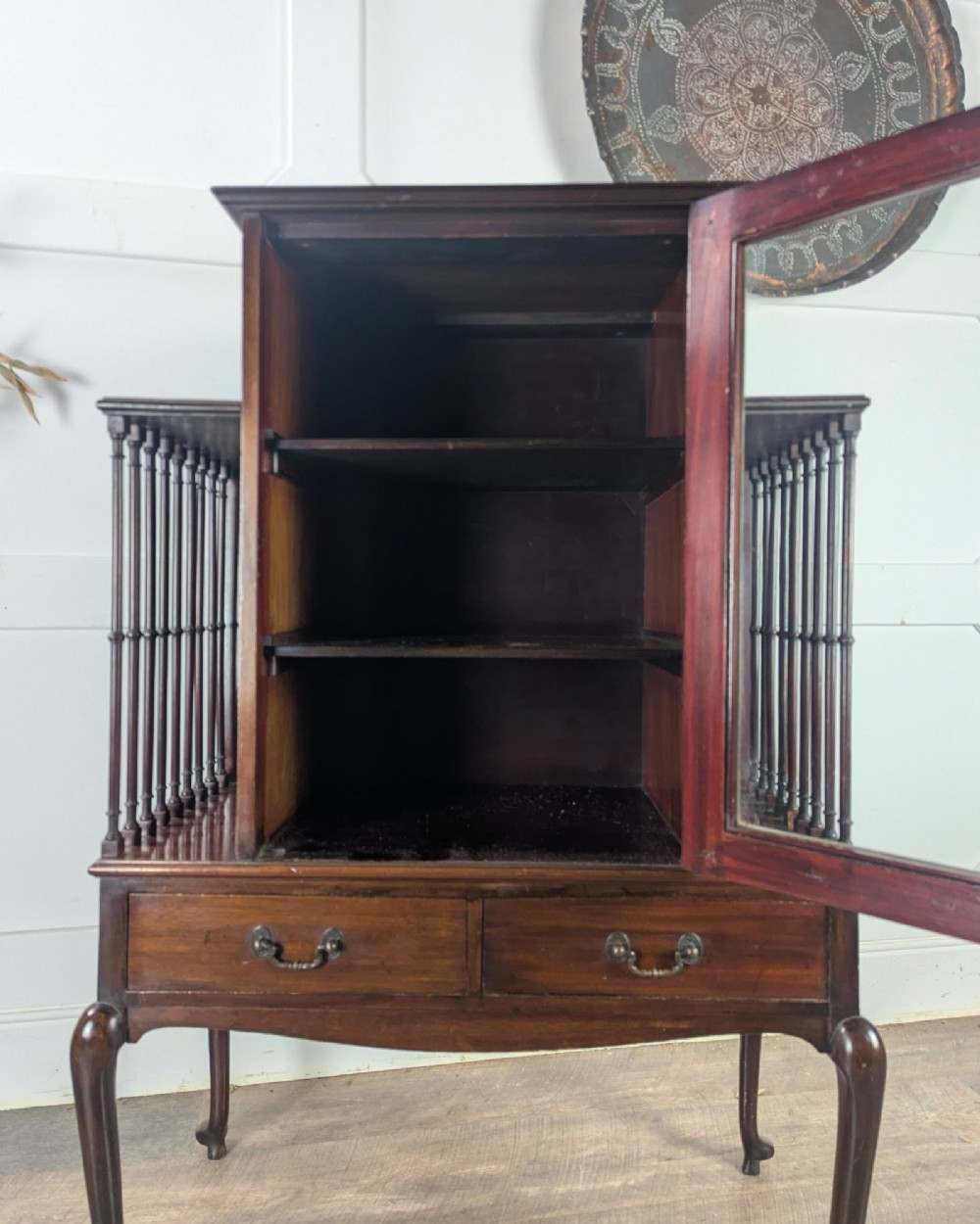 An early 20th-century mahogany music cabinet featuring a central glazed door flanked by turned spindle galleries, set above two drawers on cabriole legs. View XI