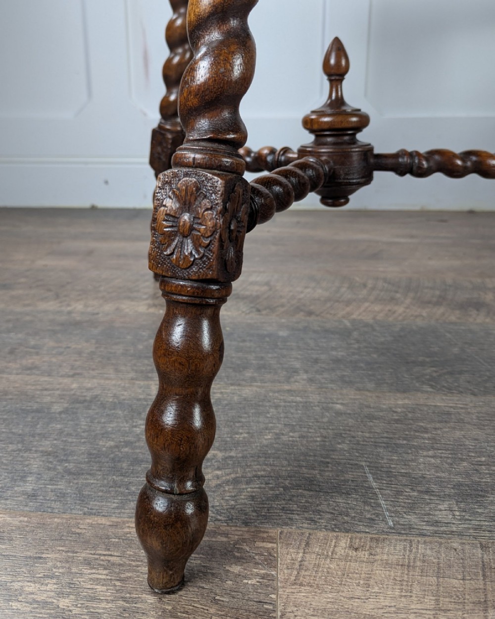 A late Victorian solid dark oak side table with an octagonal top, three barley twist legs, carved block knees, and a central turned finial on the stretcher base. View V