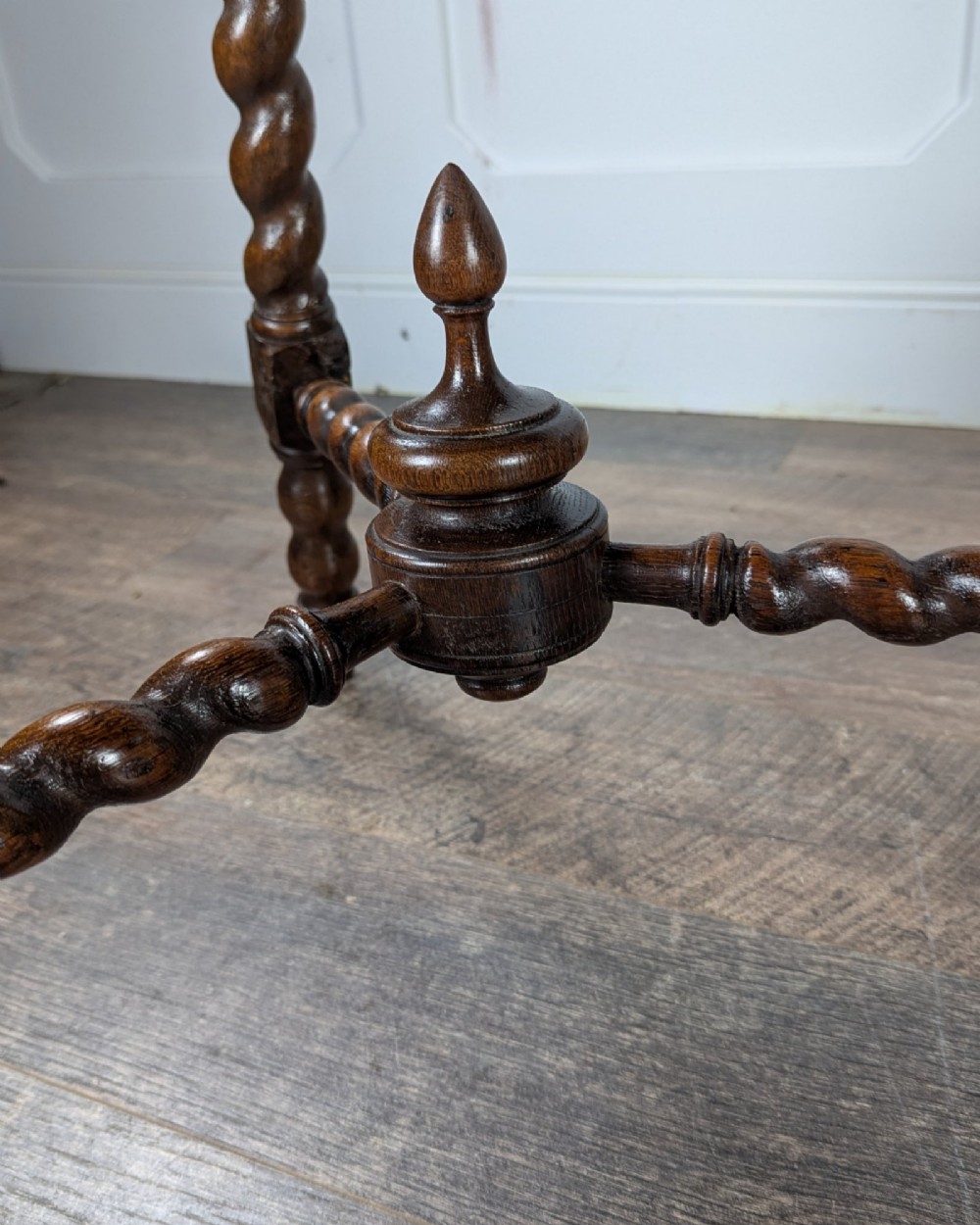 A late Victorian solid dark oak side table with an octagonal top, three barley twist legs, carved block knees, and a central turned finial on the stretcher base. View VI