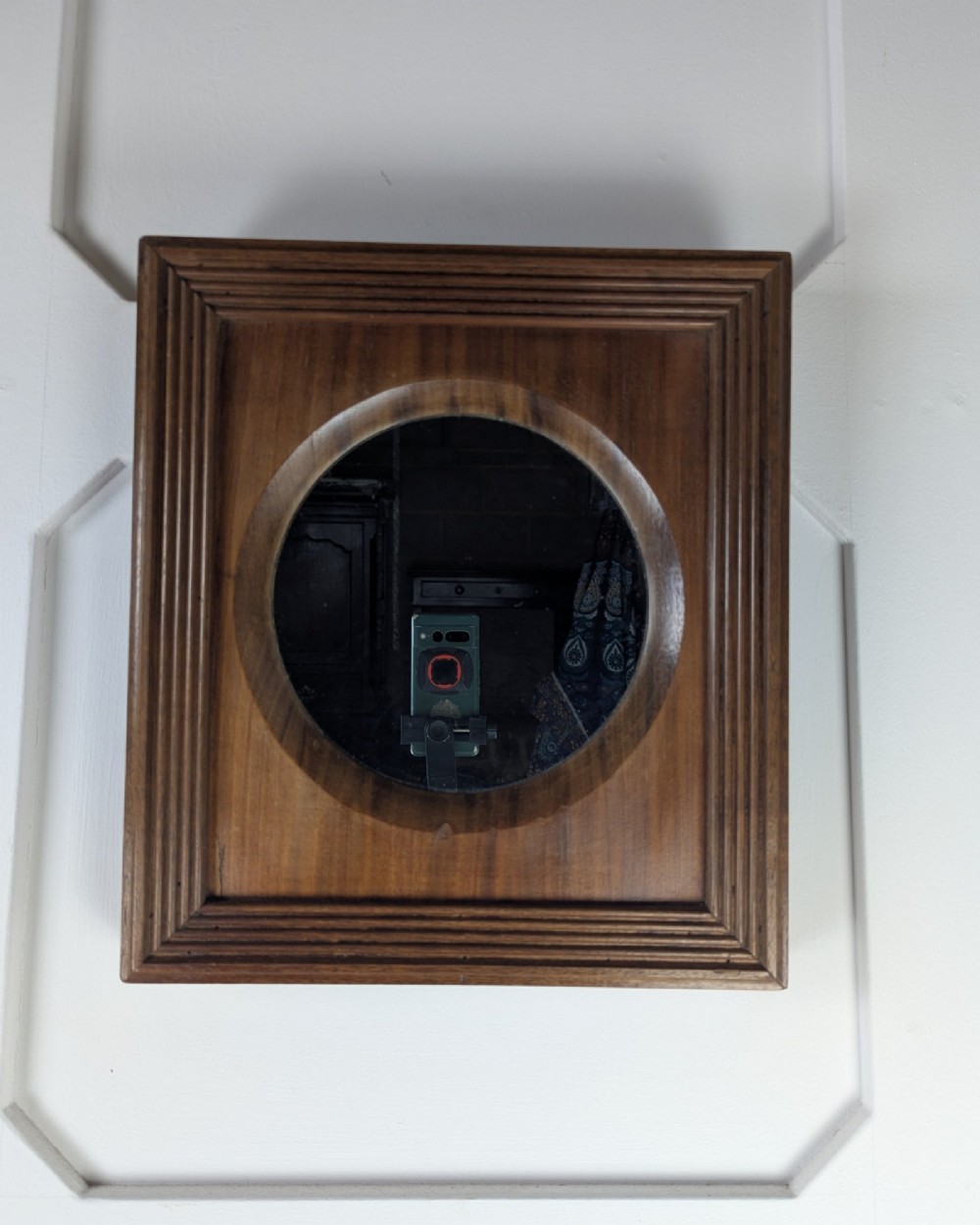 A square dark mahogany frame featuring stepped outer mouldings and a central circular mirror reflection. View IV