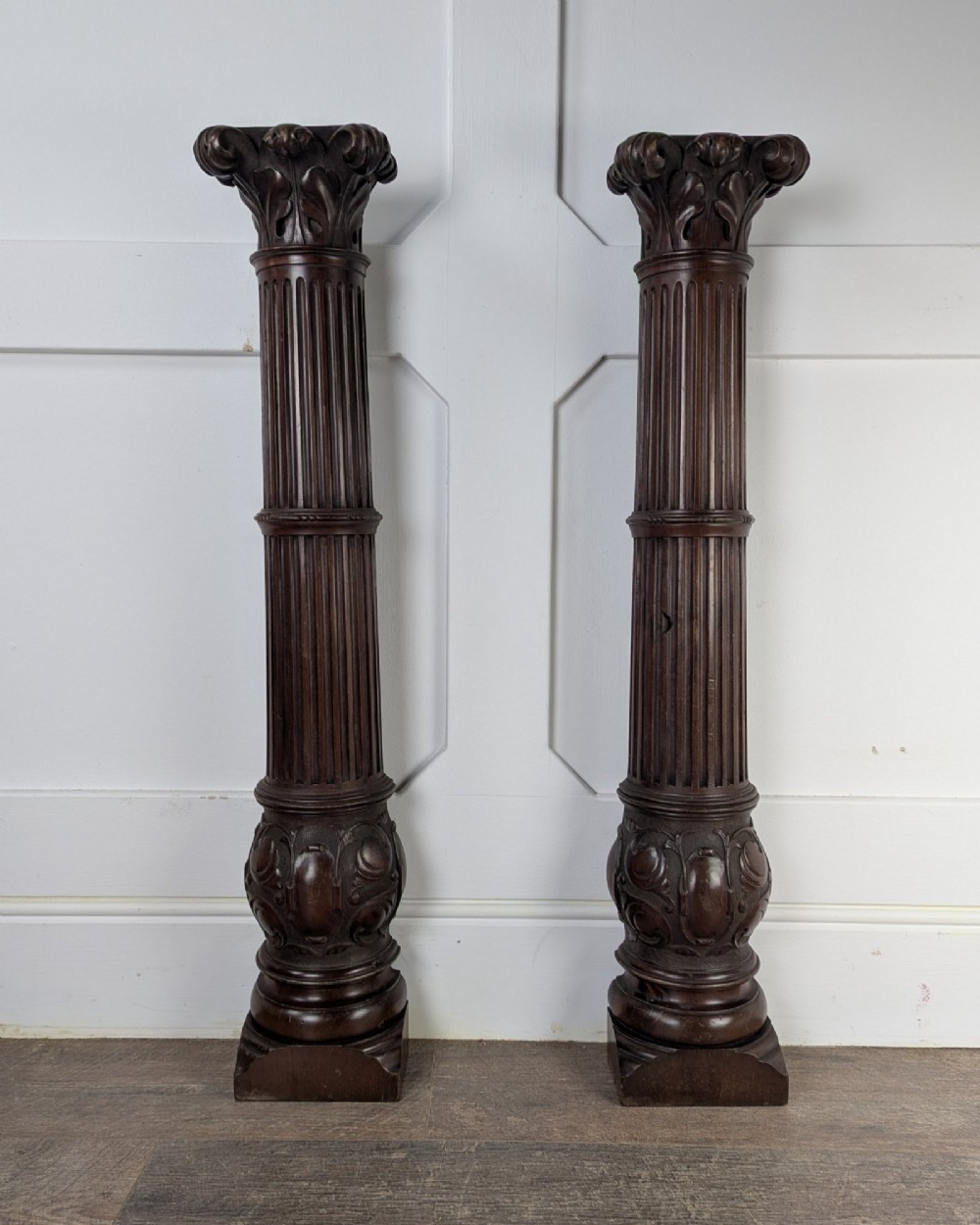 A pair of dark carved mahogany half columns featuring Corinthian capitals, reeded shafts, and carved bulbous bases. View II