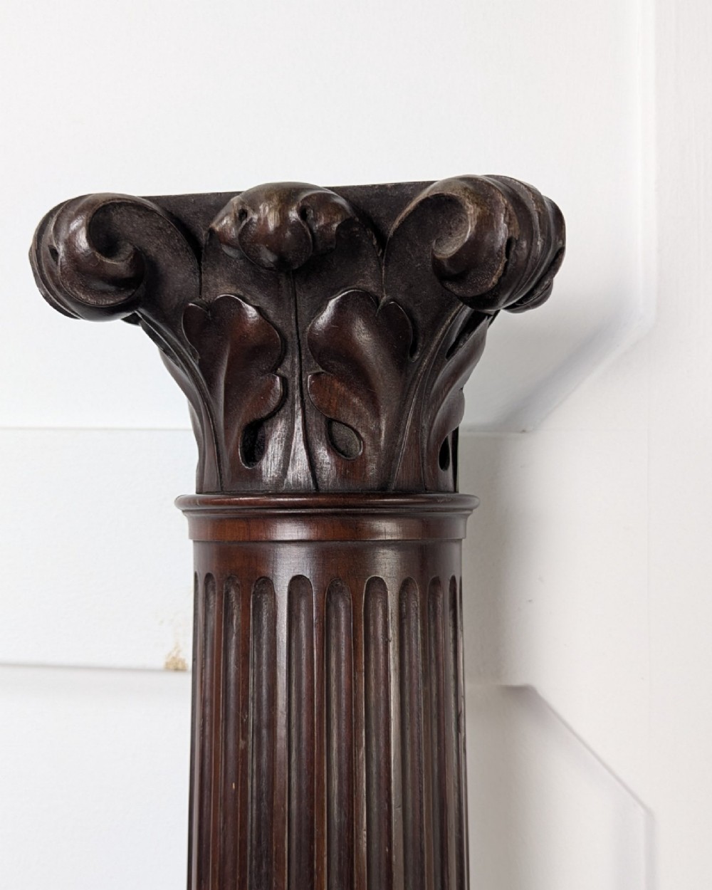 A pair of dark carved mahogany half columns featuring Corinthian capitals, reeded shafts, and carved bulbous bases. View III