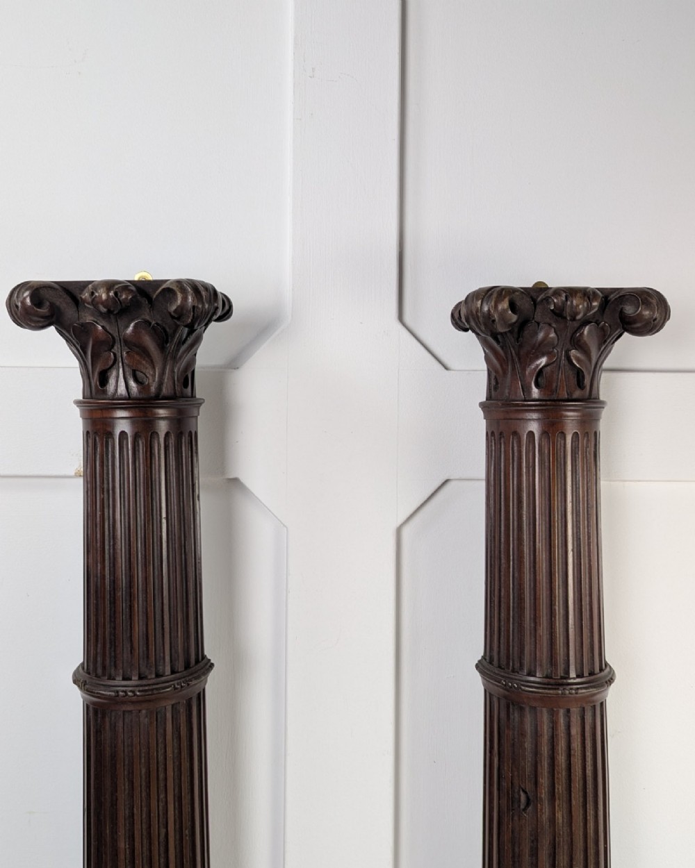A pair of dark carved mahogany half columns featuring Corinthian capitals, reeded shafts, and carved bulbous bases. View V