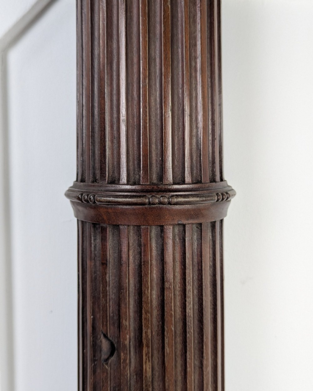 A pair of dark carved mahogany half columns featuring Corinthian capitals, reeded shafts, and carved bulbous bases. View VI