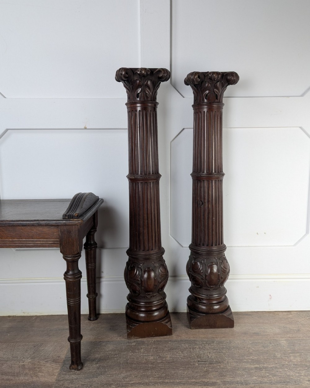 A pair of dark carved mahogany half columns featuring Corinthian capitals, reeded shafts, and carved bulbous bases. View IX