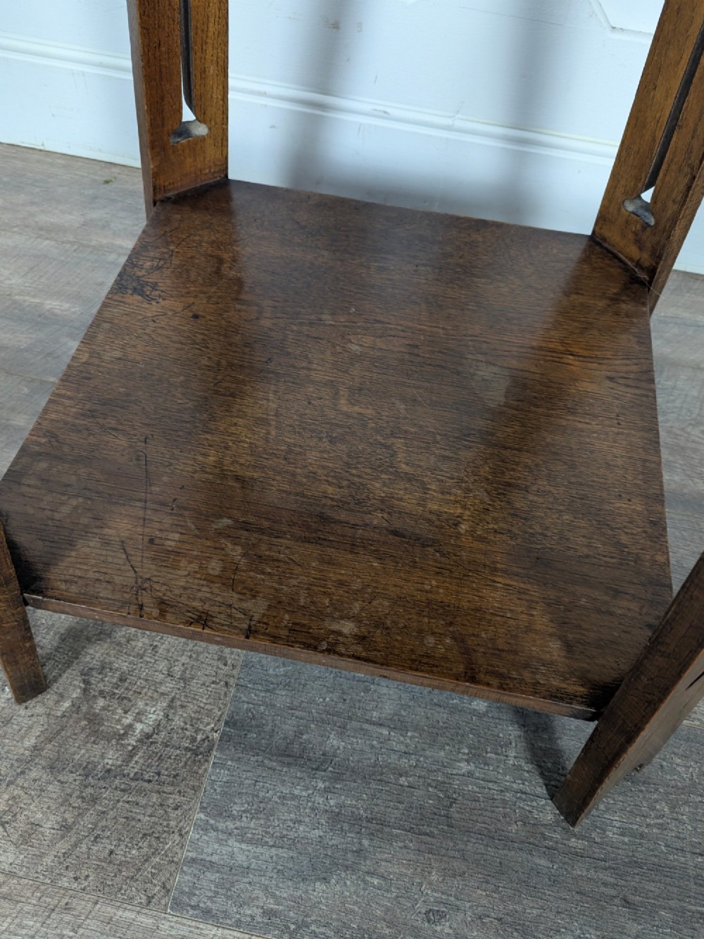 A solid oak Art Nouveau side table featuring splayed legs with spade-shaped cutouts and a lower square undertier shelf. View IX