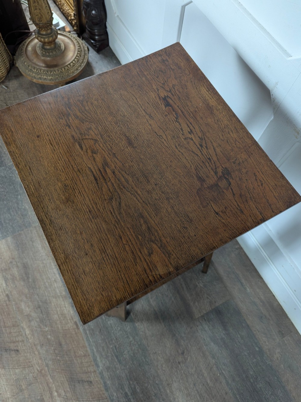 A solid oak Art Nouveau side table featuring splayed legs with spade-shaped cutouts and a lower square undertier shelf. View X