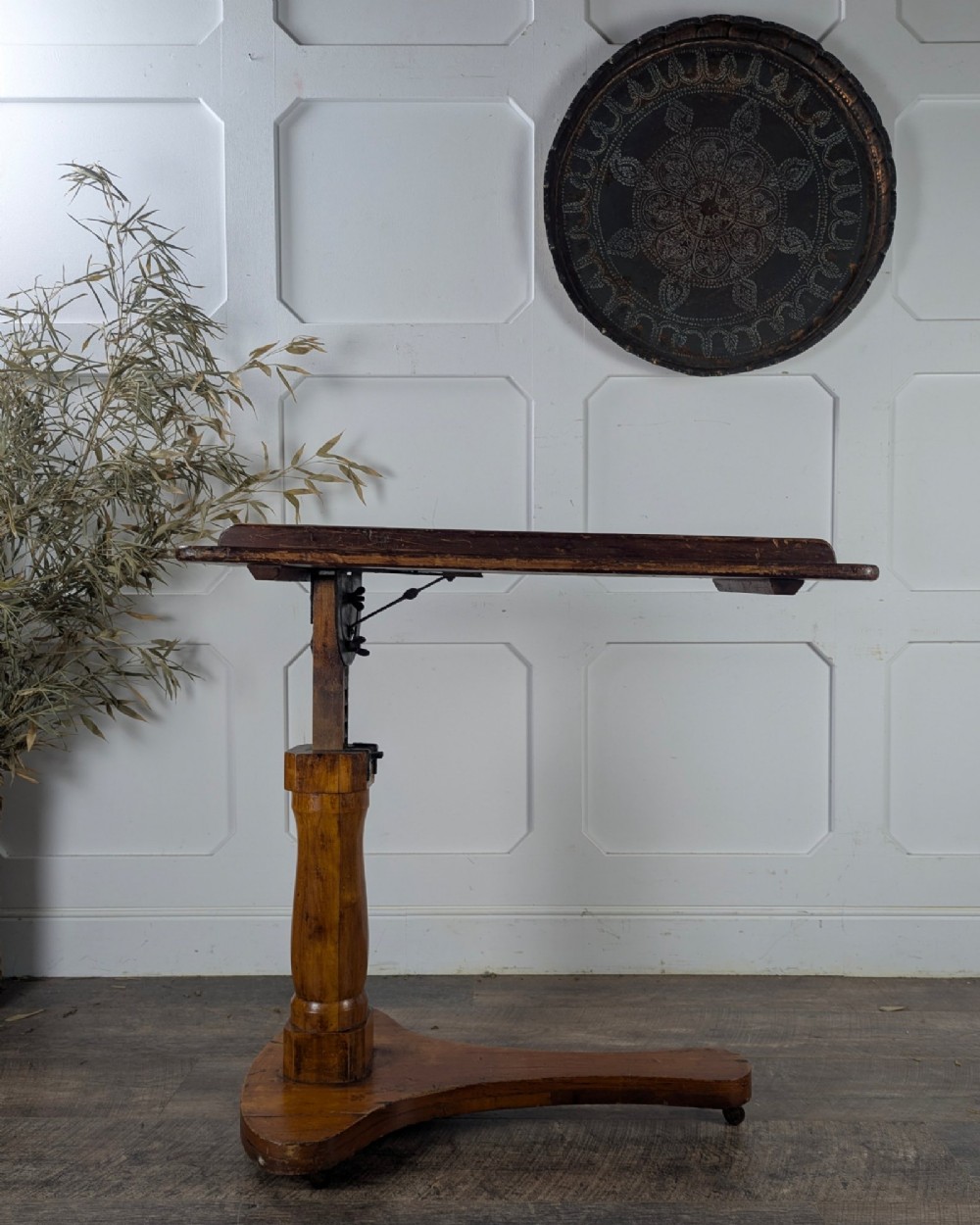 An early 20th-century pine reading table featuring an adjustable tilting top, a central turned support column, and a shaped base on small castors. View IV