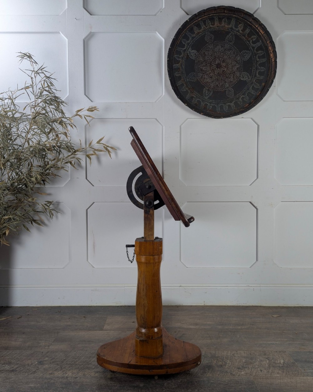 An early 20th-century pine reading table featuring an adjustable tilting top, a central turned support column, and a shaped base on small castors. View VI