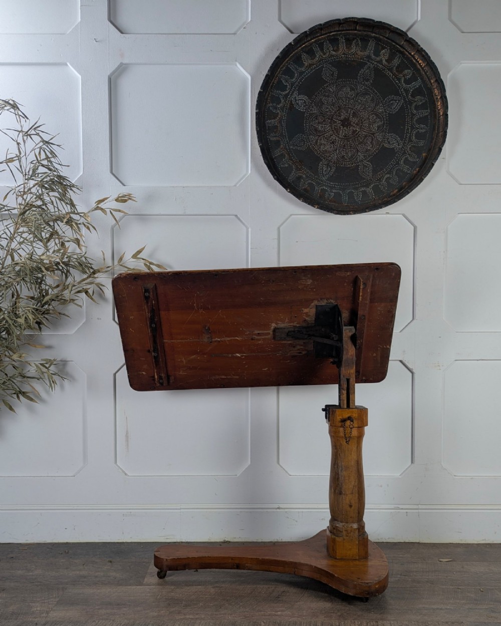 An early 20th-century pine reading table featuring an adjustable tilting top, a central turned support column, and a shaped base on small castors. View VII