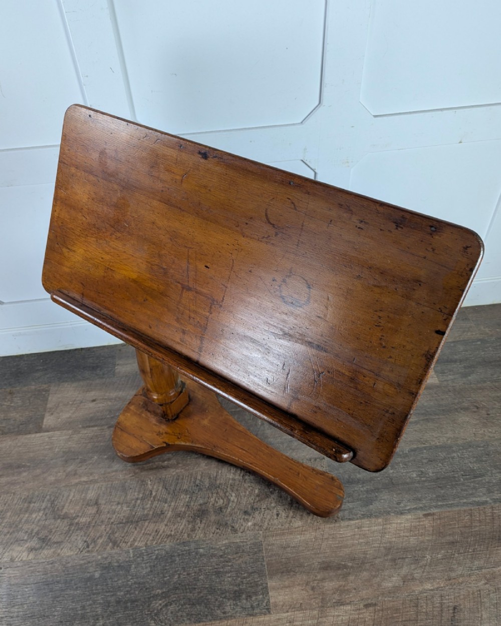 An early 20th-century pine reading table featuring an adjustable tilting top, a central turned support column, and a shaped base on small castors. View XI