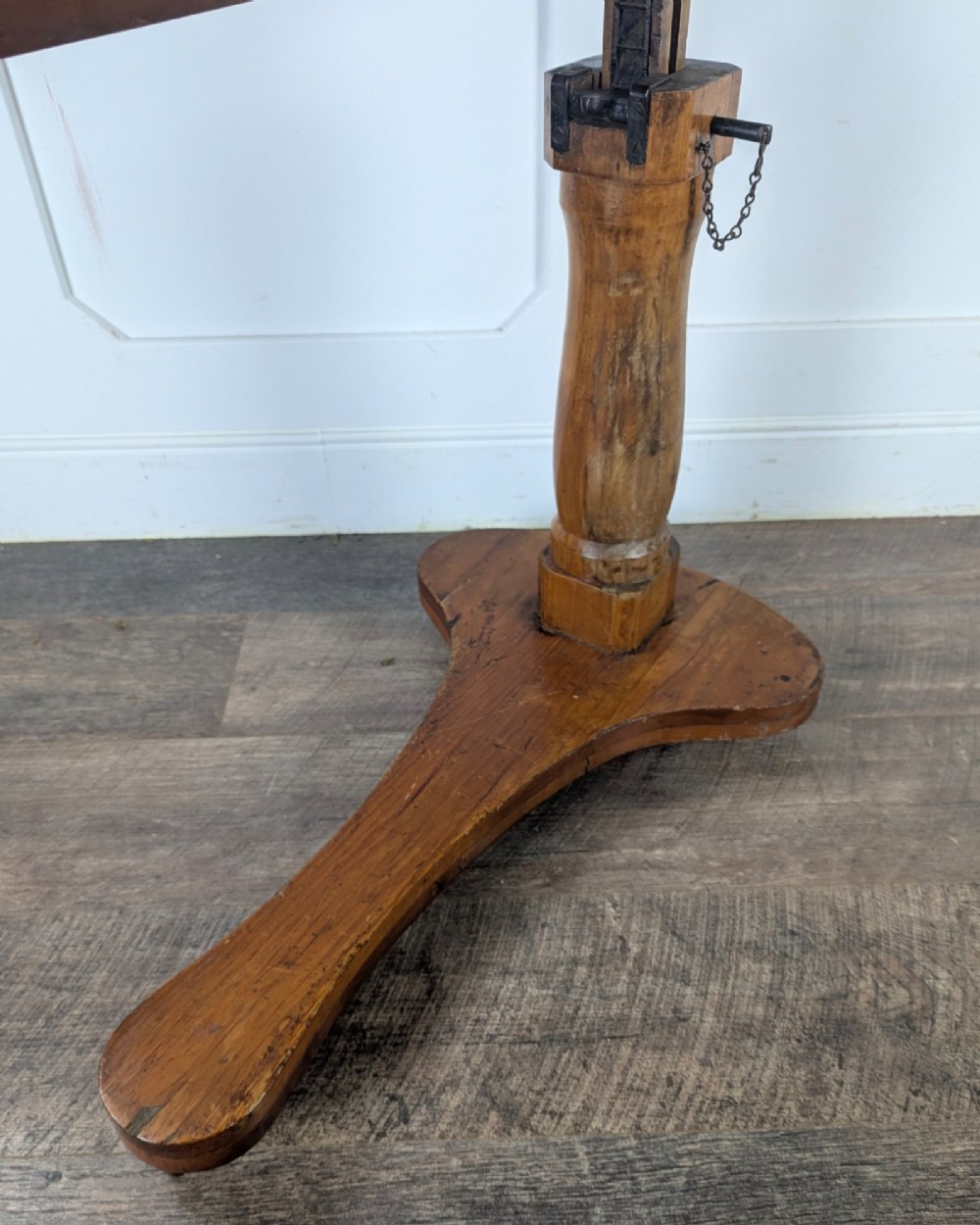 An early 20th-century pine reading table featuring an adjustable tilting top, a central turned support column, and a shaped base on small castors. View XII