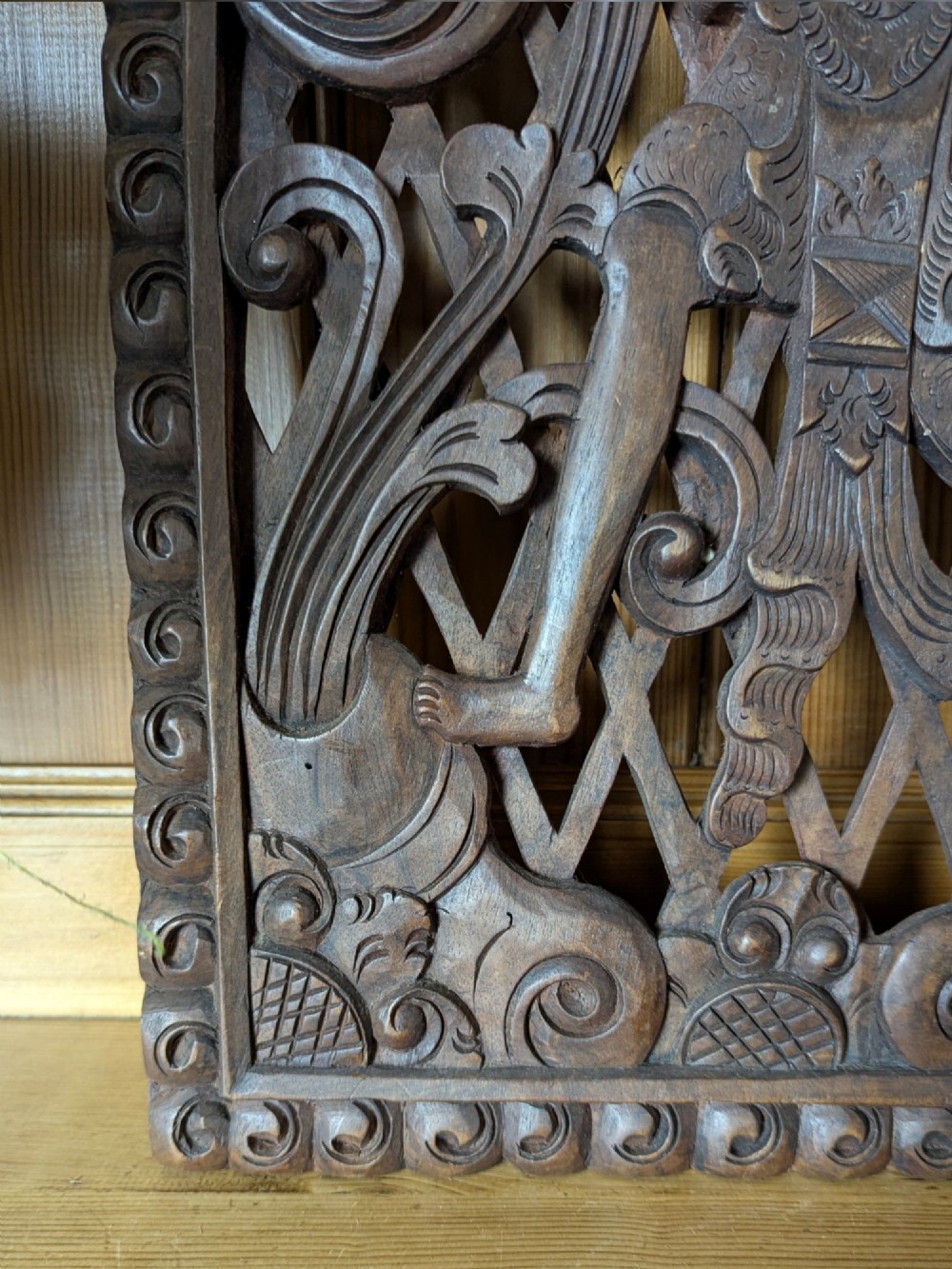 A rectangular dark teak wall panel hand-carved in high relief with an openwork Balinese mythological figure framed by intricate scrolling foliage. View IV