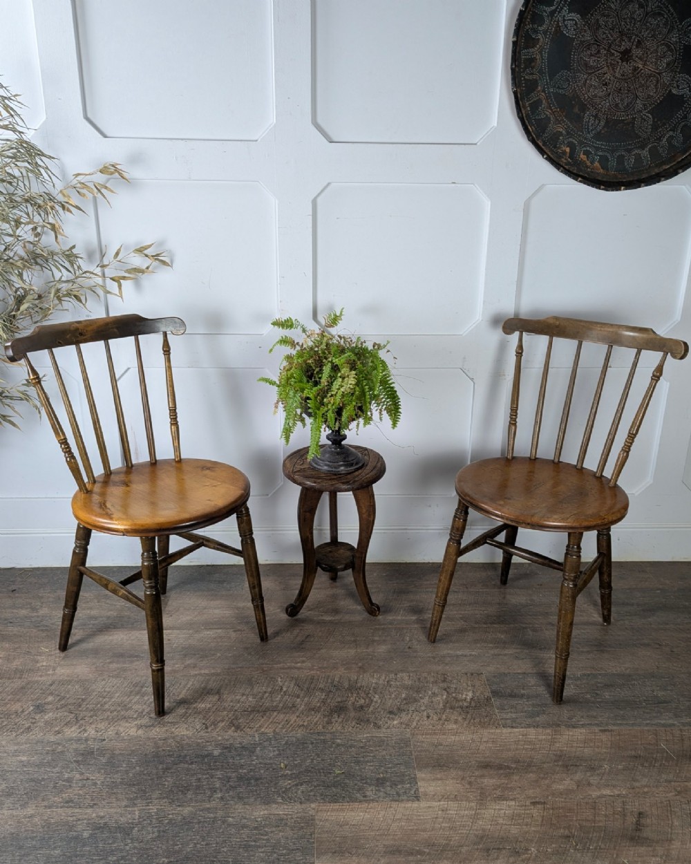 A pair of early twentieth-century wooden Dinco penny chairs featuring spindle backs, turned legs, curved stretchers, and shaped seats. View II