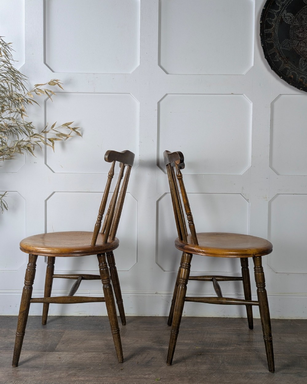 A pair of early twentieth-century wooden Dinco penny chairs featuring spindle backs, turned legs, curved stretchers, and shaped seats. View V