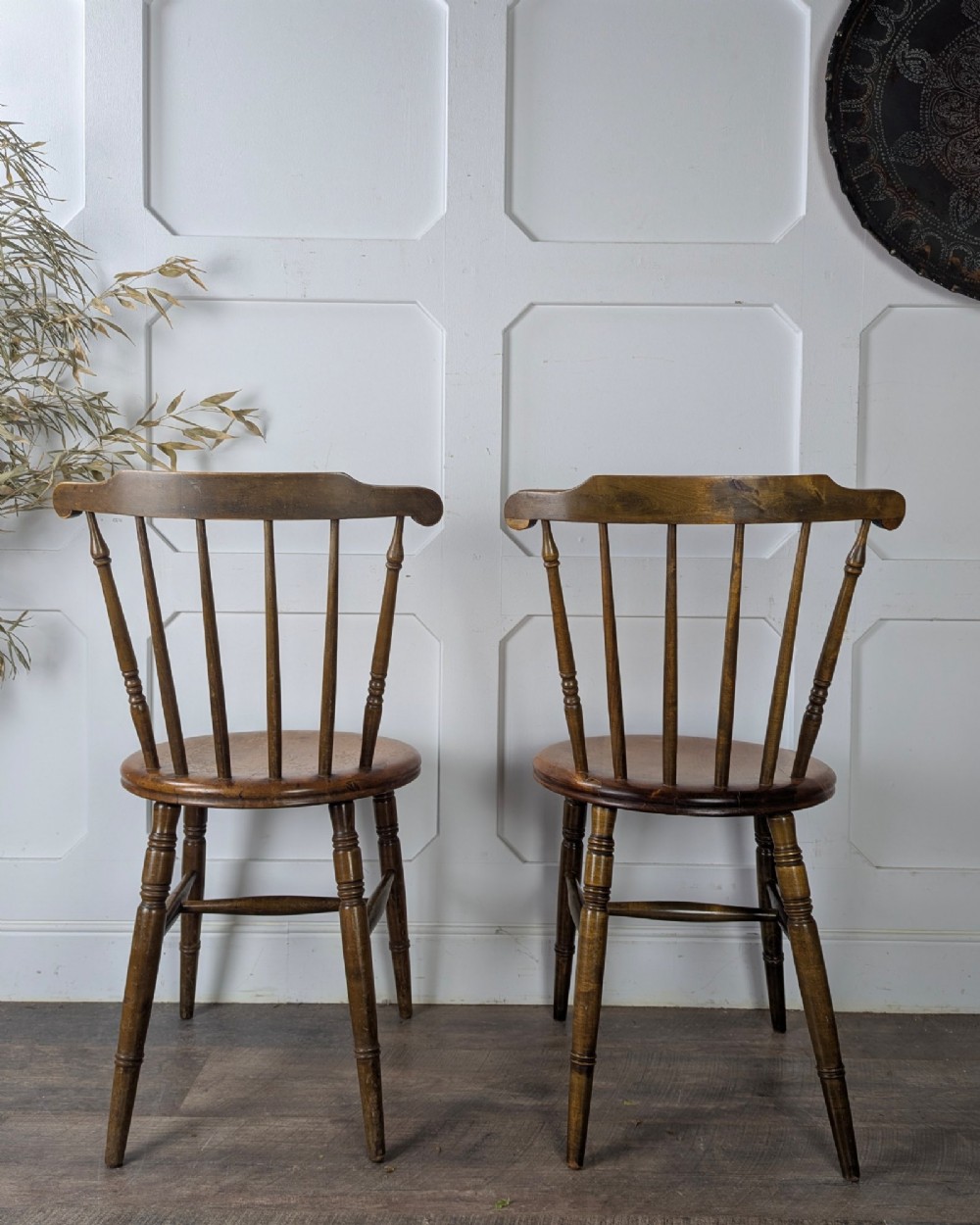 A pair of early twentieth-century wooden Dinco penny chairs featuring spindle backs, turned legs, curved stretchers, and shaped seats. View VI