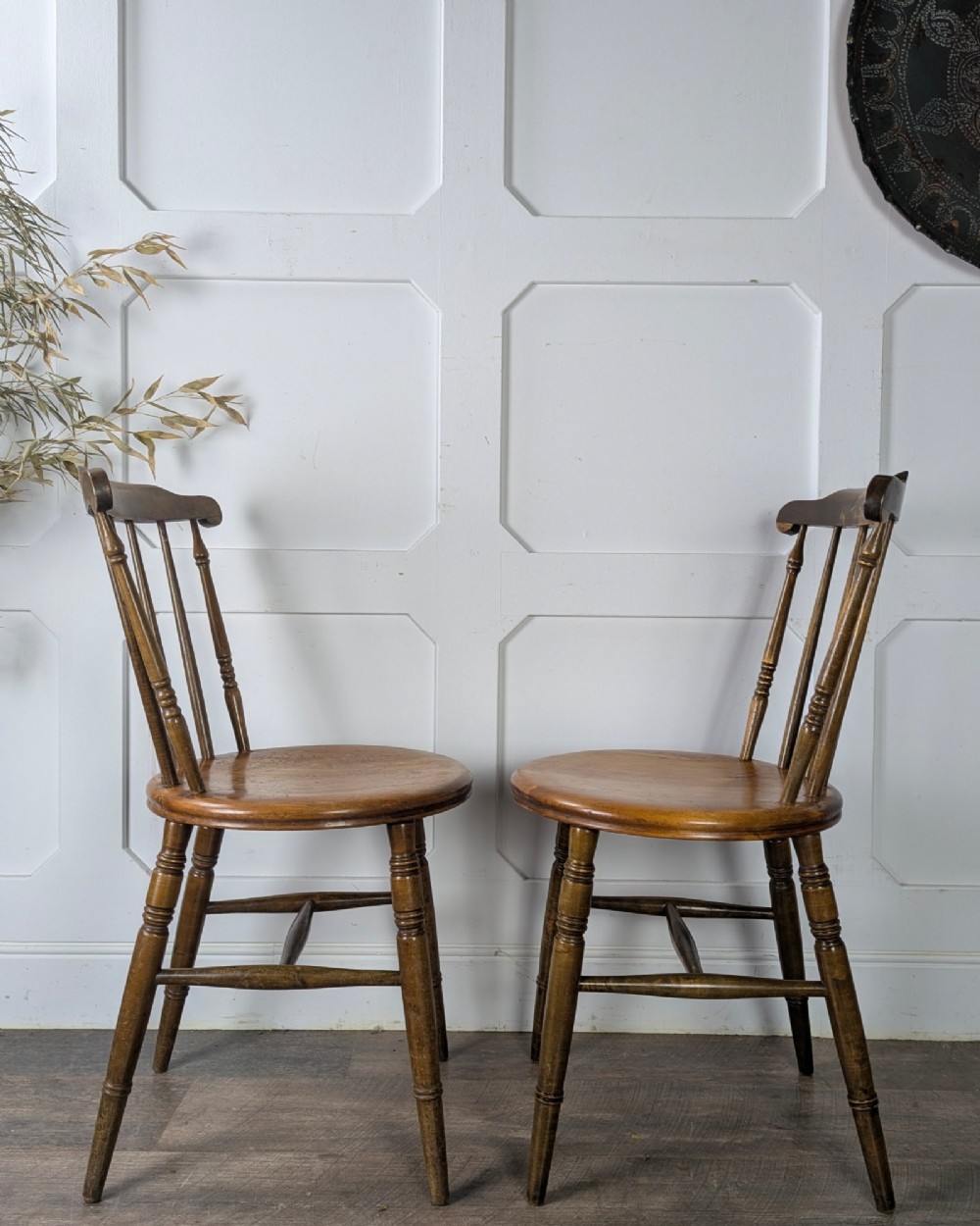 A pair of early twentieth-century wooden Dinco penny chairs featuring spindle backs, turned legs, curved stretchers, and shaped seats. View VII