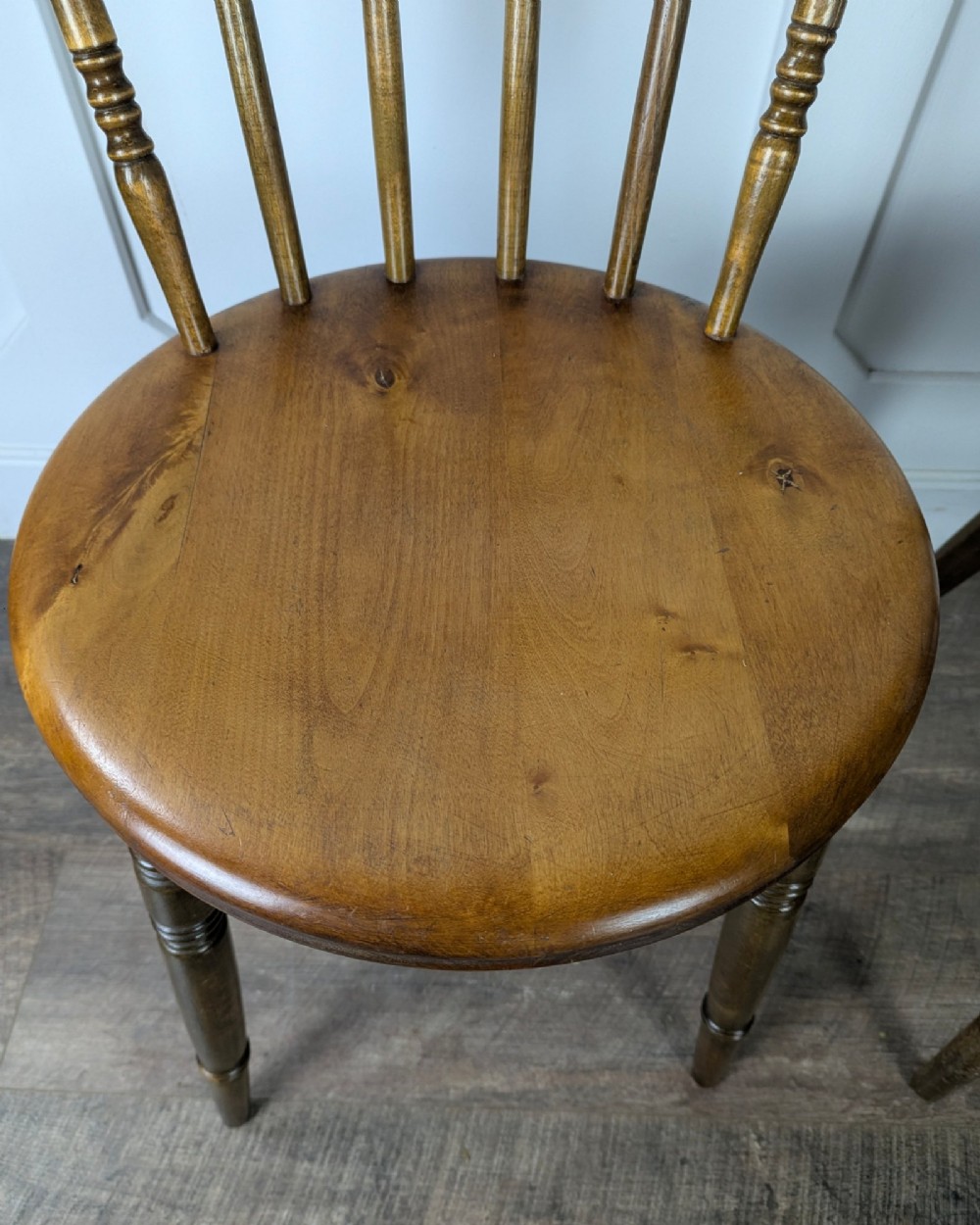 A pair of early twentieth-century wooden Dinco penny chairs featuring spindle backs, turned legs, curved stretchers, and shaped seats. View VIII